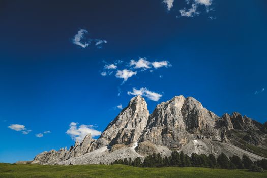 Stunning mountain peak with rocky cliffs under a vibrant blue sky, perfect for outdoor adventures.