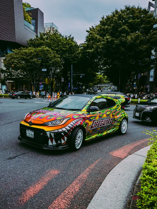 Free Vibrant customized car driving through Shibuya, Tokyo, showcasing urban street life. Stock Photo