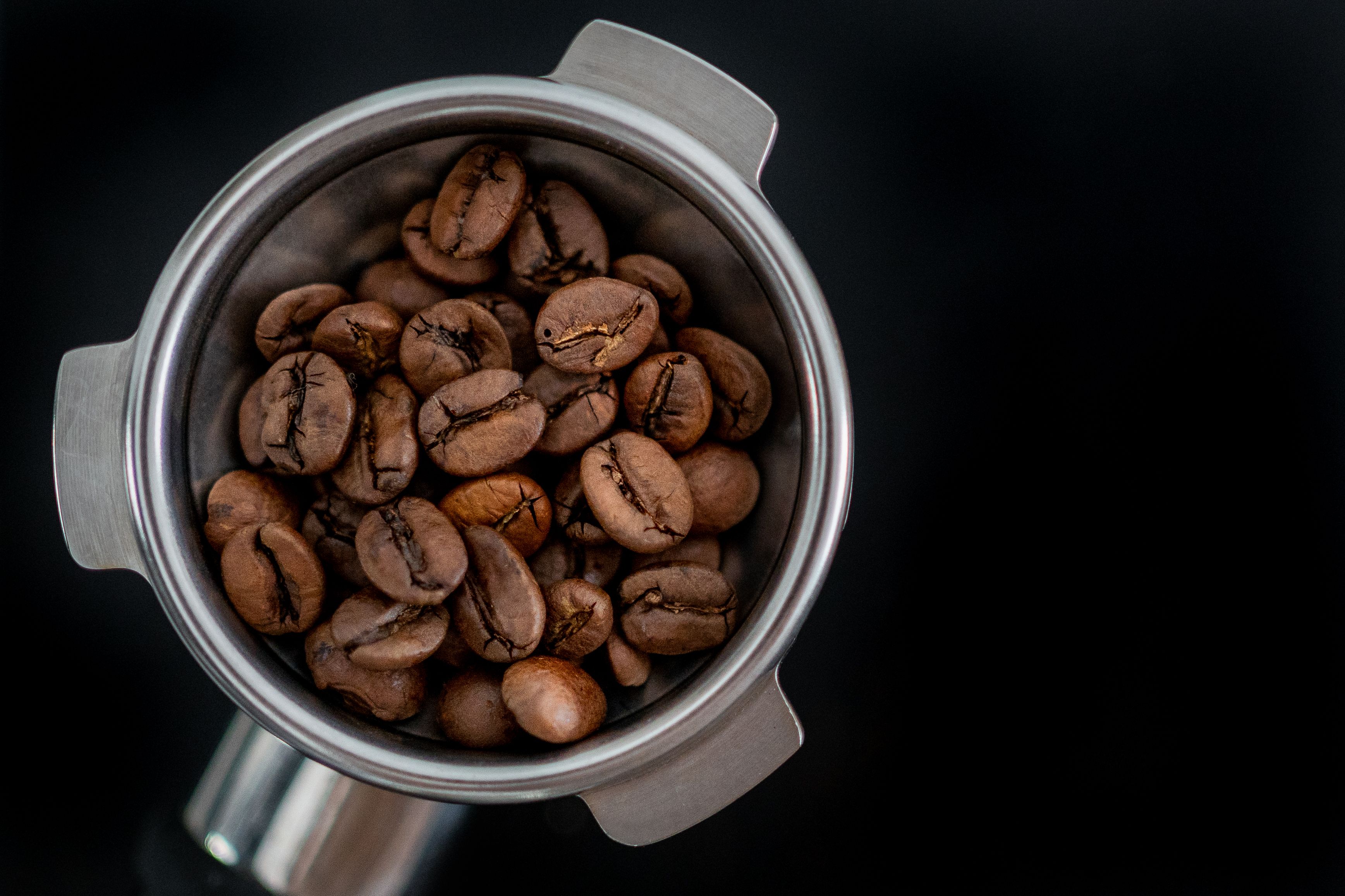 Close-up of coffee beans in a portafilter, perfect for coffee-themed designs.