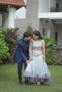 A couple in traditional attire standing in front of a house