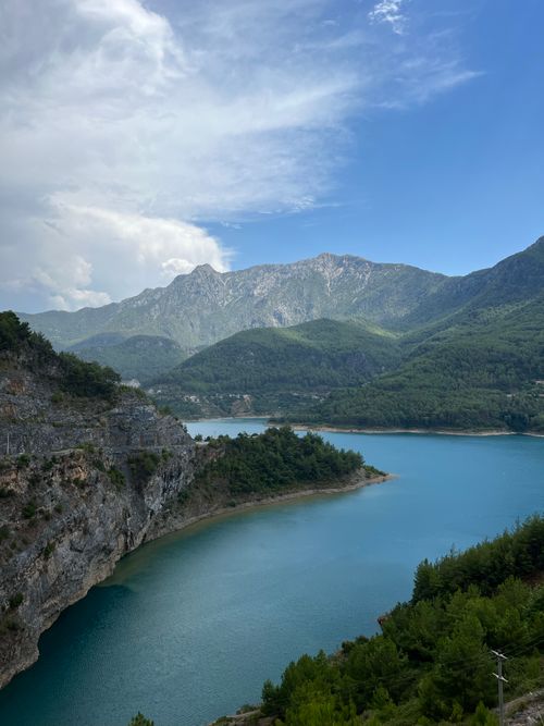 Free Beautiful mountain lake surrounded by lush green hills and clear blue sky, ideal for travel and adventure lovers. Stock Photo