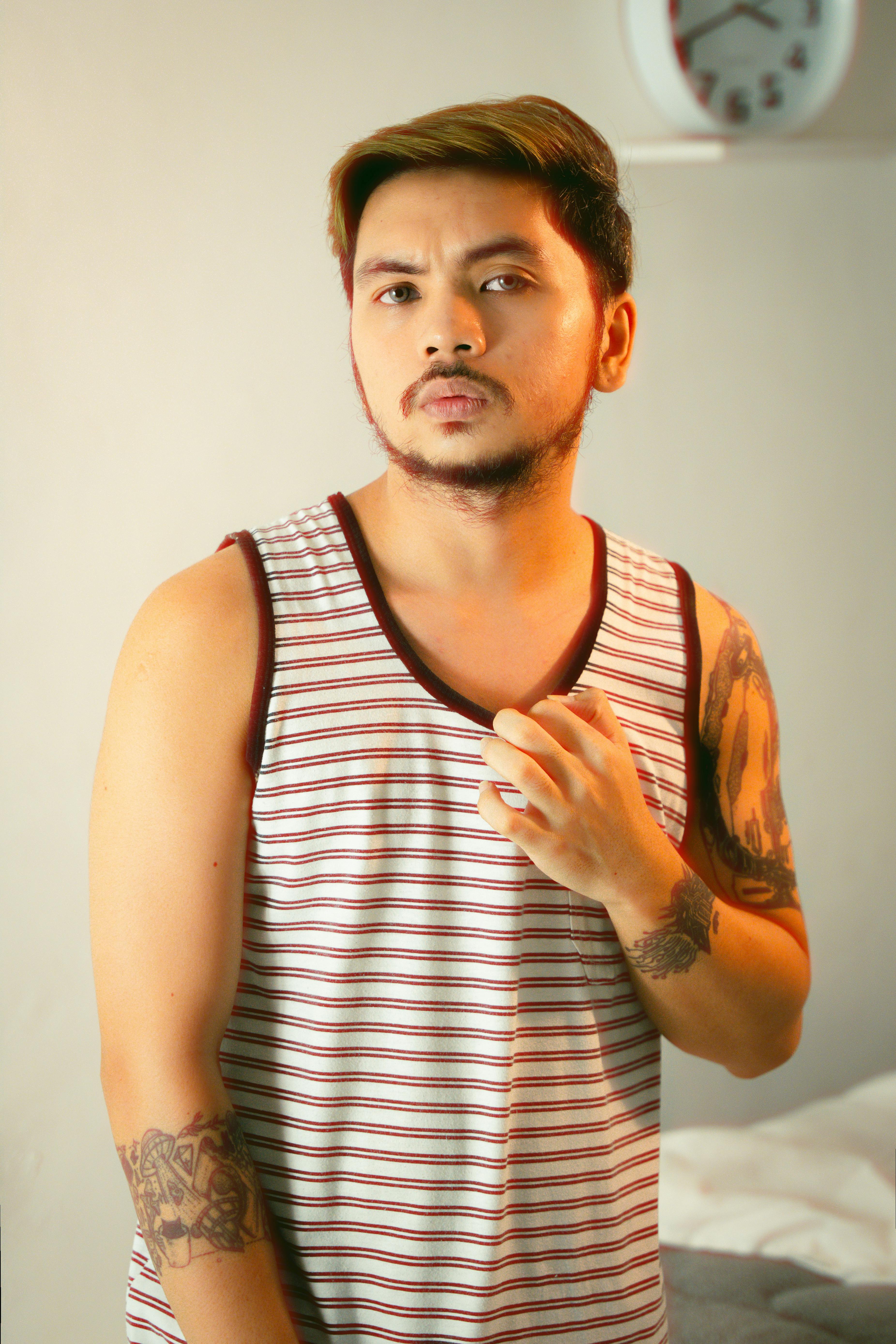 Stylish young man with tattoos posing confidently indoors.