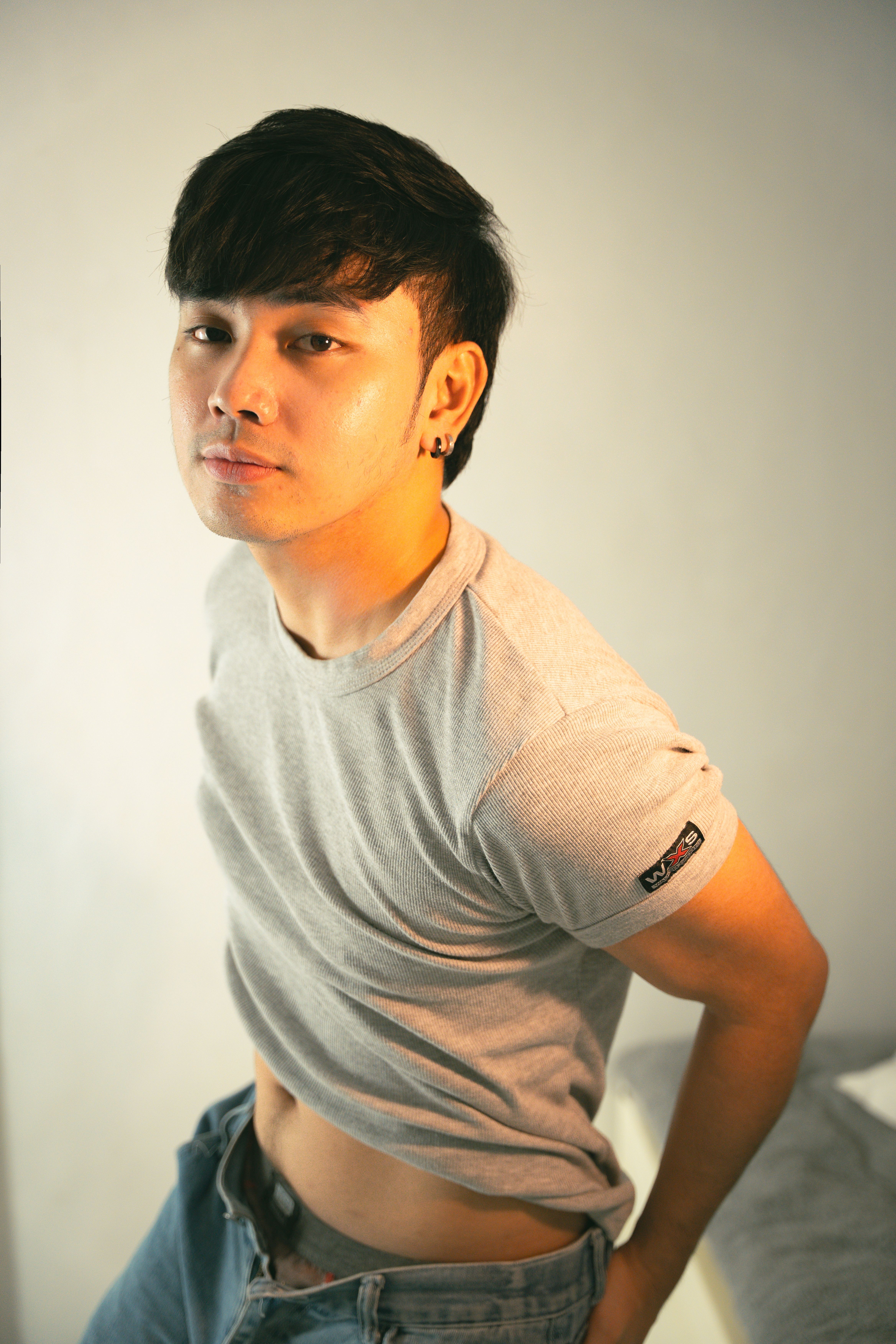 Trendy young man poses casually indoors, expressing individuality in a modern portrait.