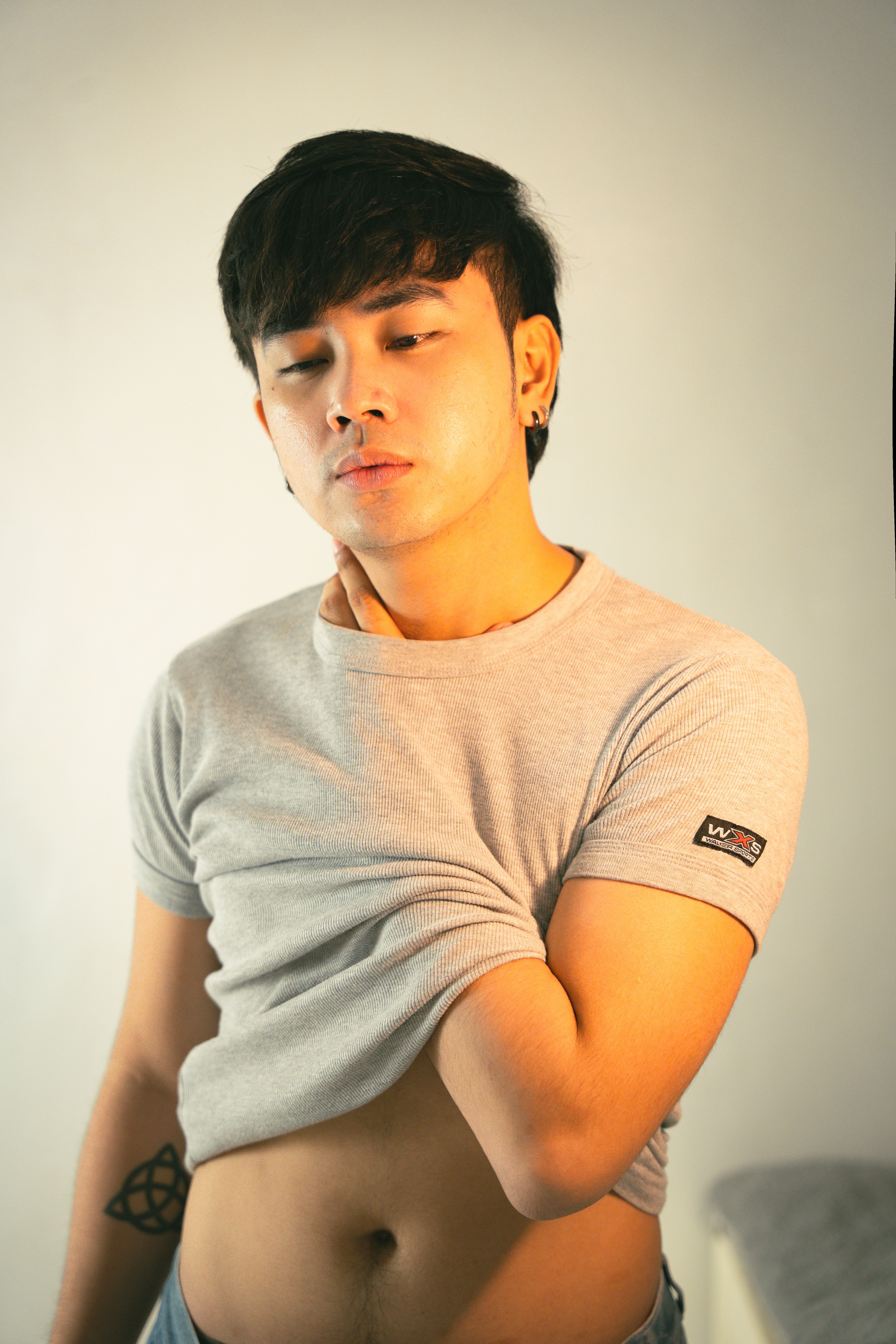 Young Asian man in casual wear posing with confident expression indoors. Perfect for lifestyle and fashion contexts.