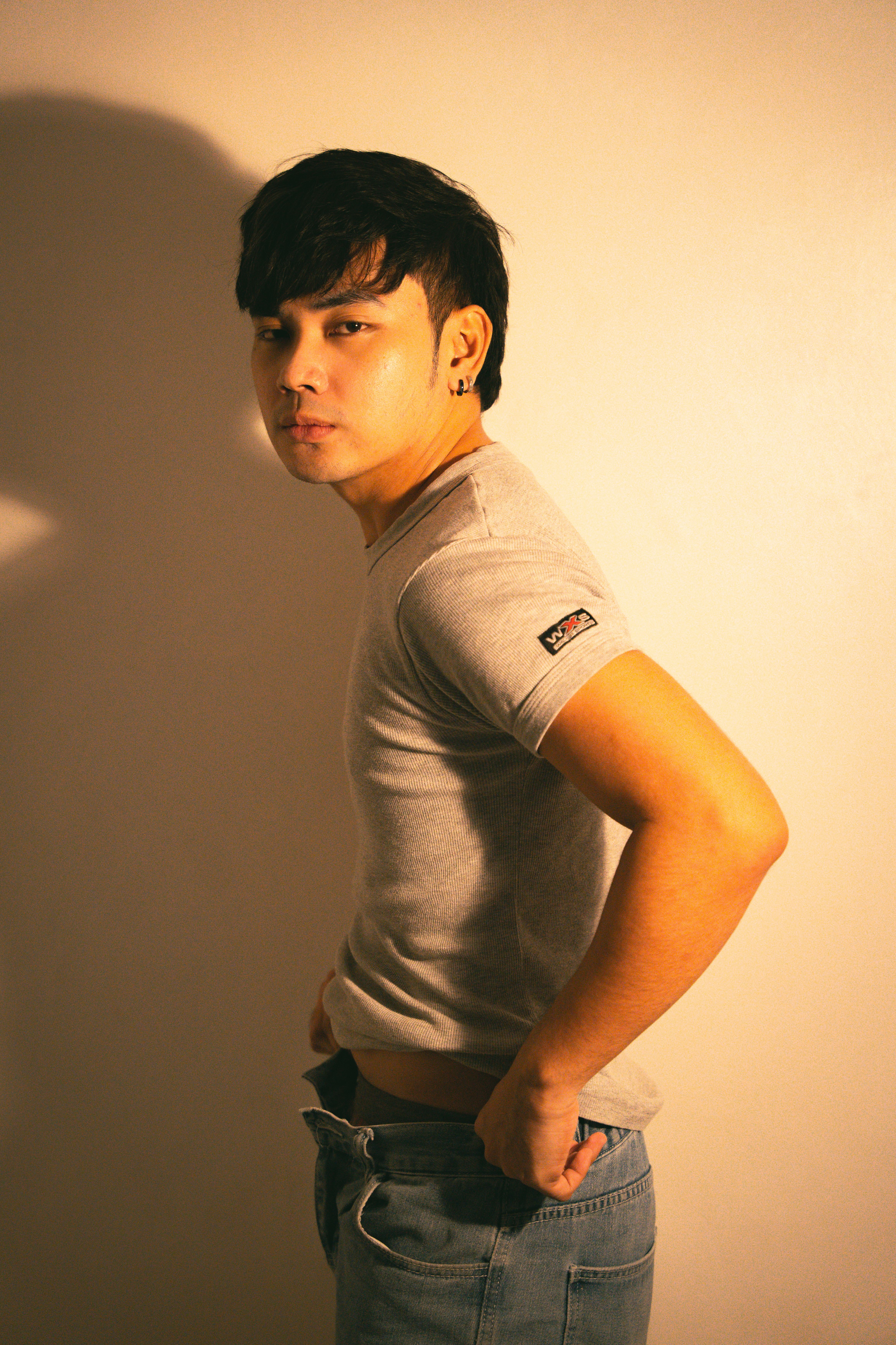 Portrait of a trendy young man posing in a studio with dramatic lighting.