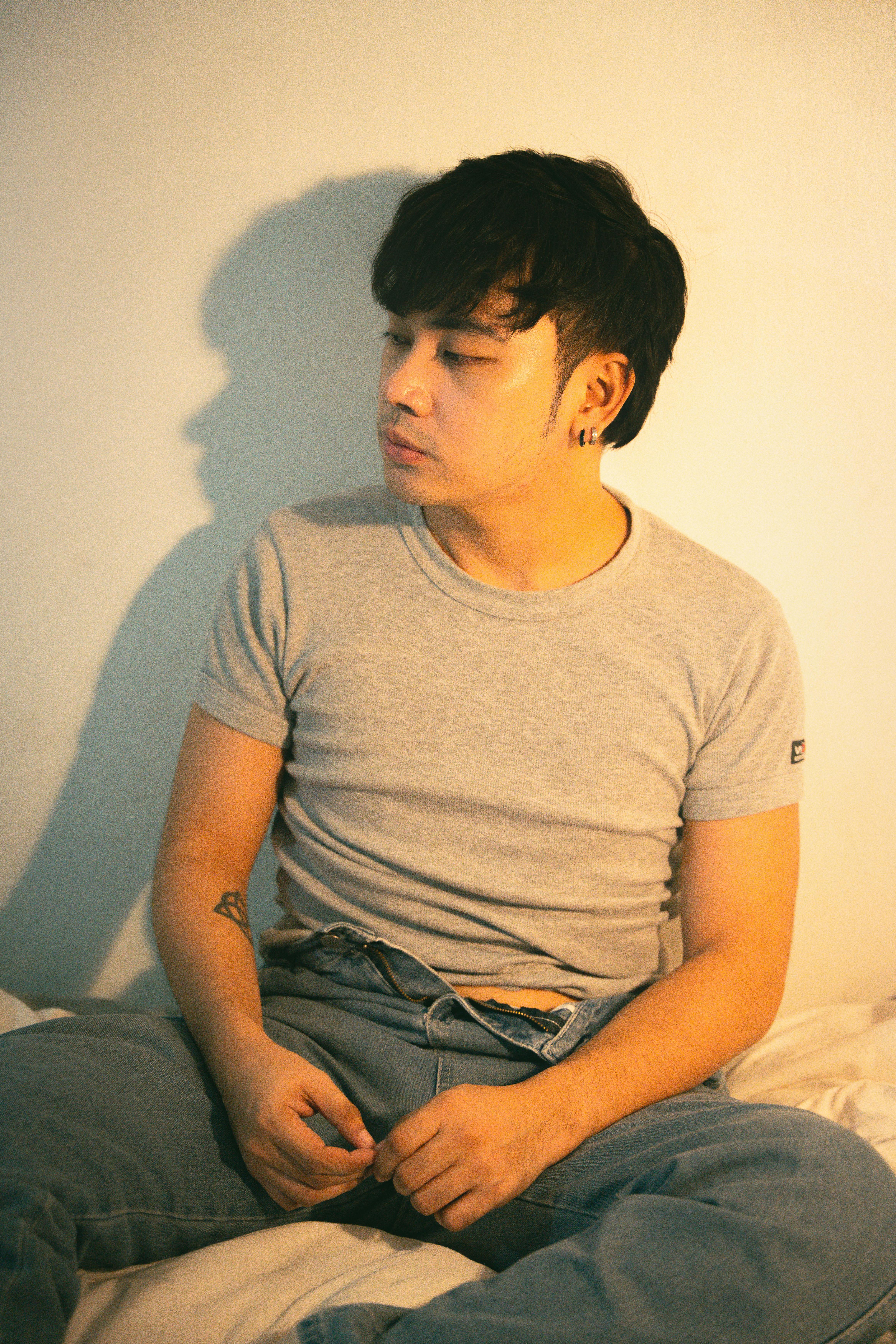 A young man sitting on a bed with his head down