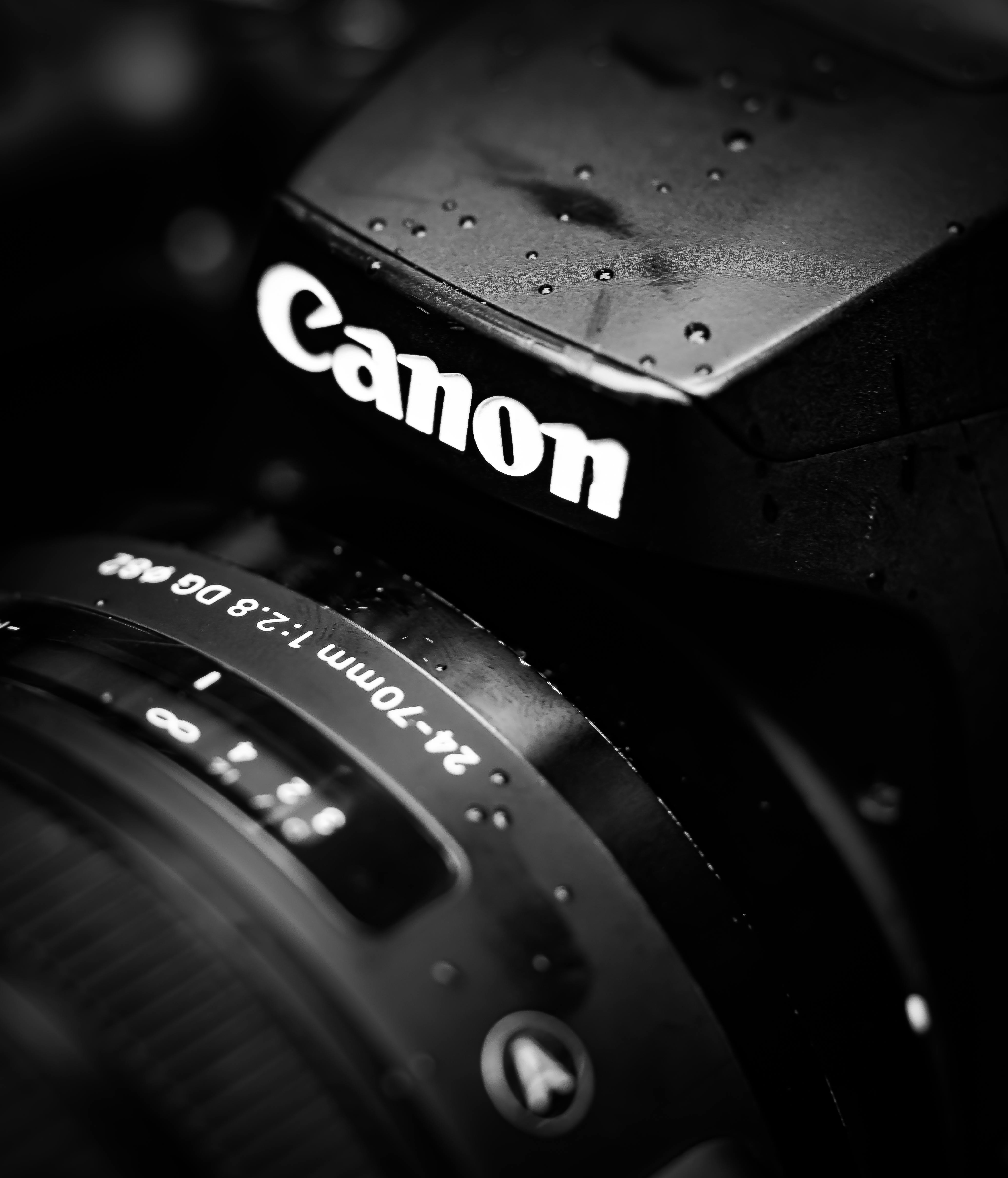 Monochromatic image focusing on a camera lens and body with water droplets for dramatic effect.
