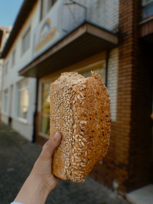 Free Hand holding a loaf of seeded bread outdoors on a city street. Stock Photo