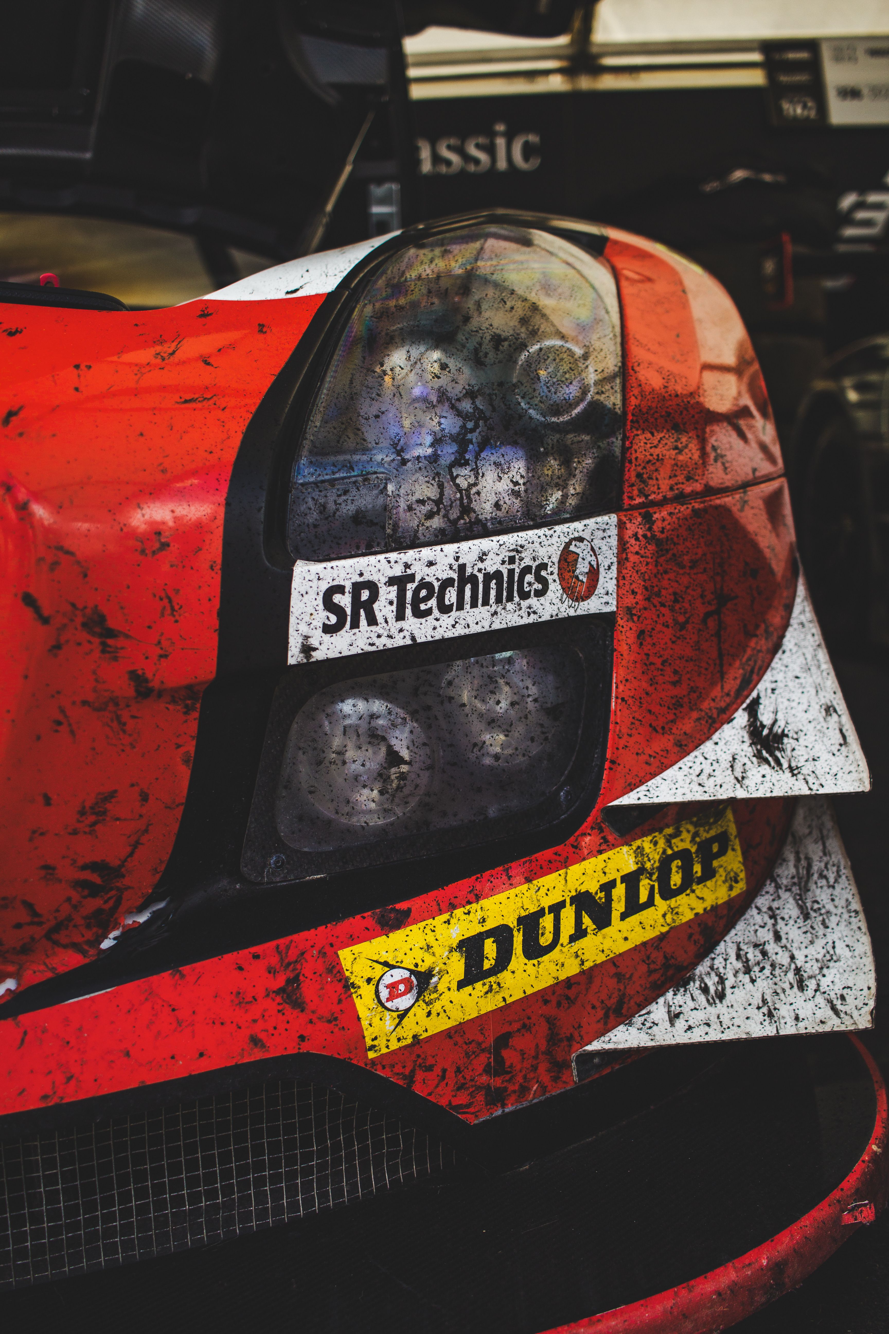 Detailed view of a dirty racing car showcasing logos at an auto exhibition.