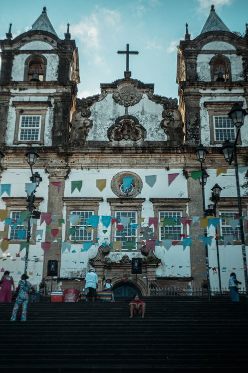 Free A historic church in Salvador, Brazil, adorned with colorful flags, capturing the vibrant street life. Stock Photo