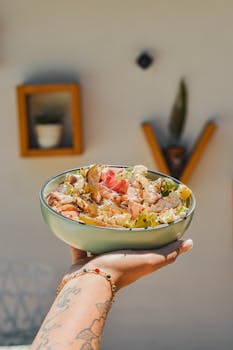 A person holding a bowl of food in front of a wall