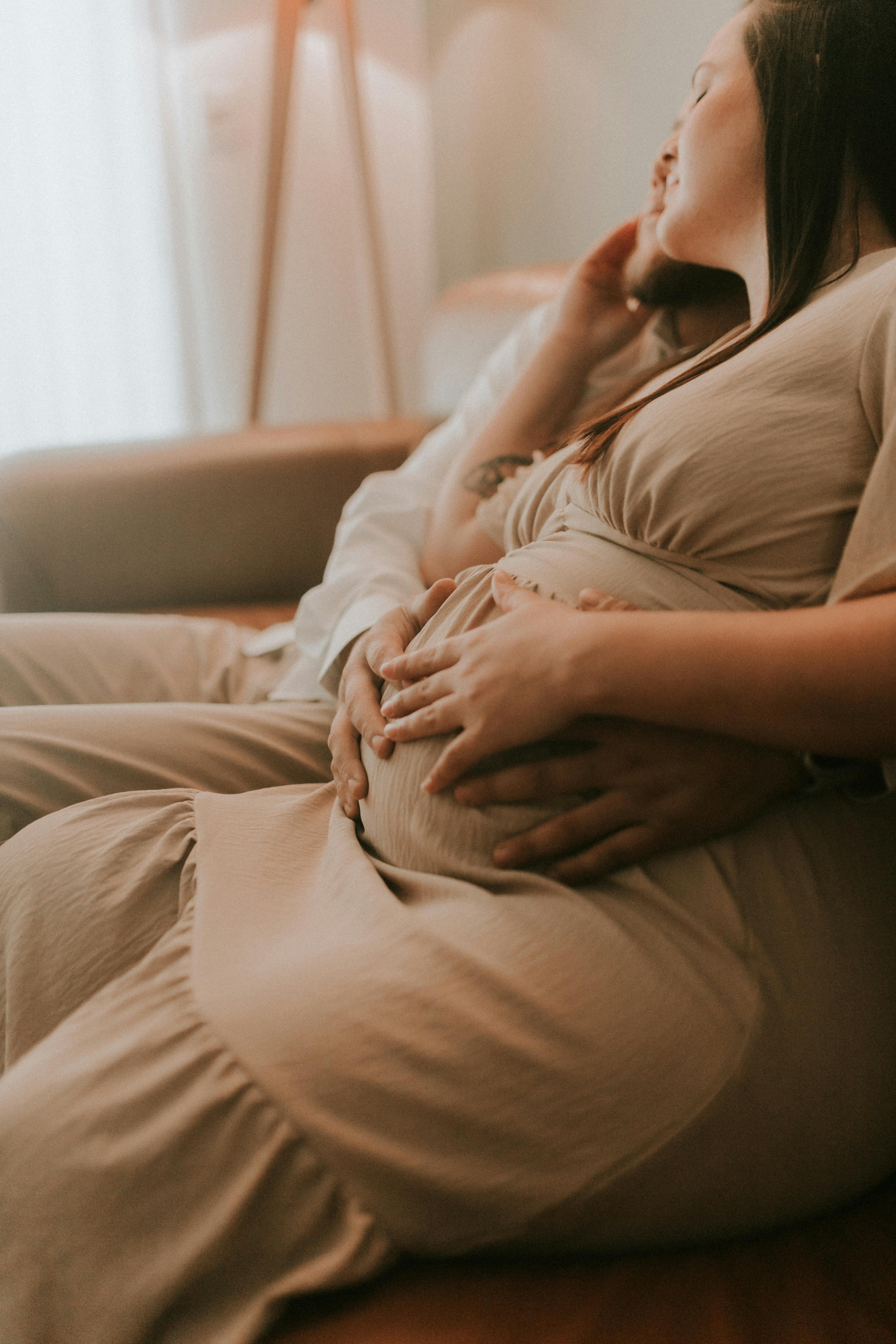 husband and his pregnant wife sitting on a sofa and embracing