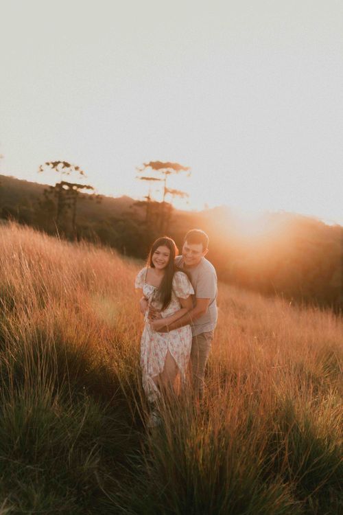 Free A couple lovingly embracing in a sunlit field, capturing a golden moment at sunset. Stock Photo