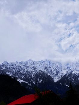 Majestic snow-covered mountain peaks with a red rooftop, capturing the essence of winter adventure.