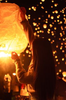 A woman releases a glowing lantern amidst a dreamy night festival in Salt Lake City.