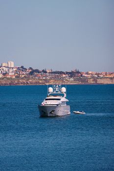 A luxury yacht cruising through Lisbon harbor with a stunning cityscape in the background.
