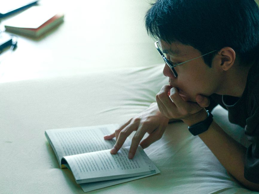 ジャカルタの屋内で本を読んでいる若者、学びとリラクゼーションに集中している。