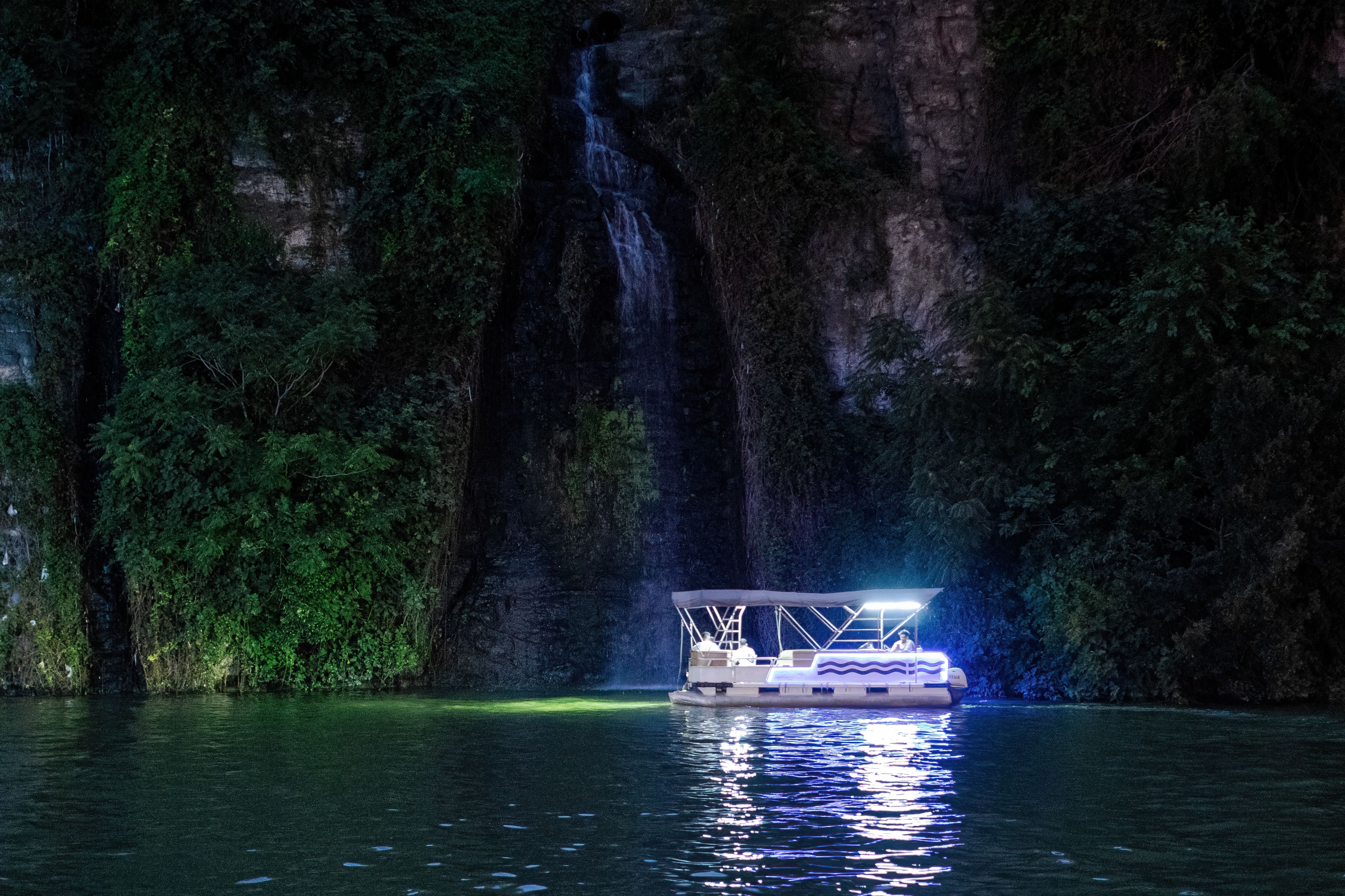 Tourist Boat by the Cliff with Waterfall at Dusk · Free Stock Photo
