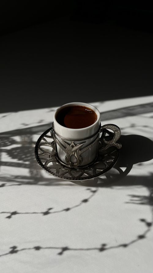 Free An espresso cup in an ornate holder projects intricate shadows, creating a vintage still life. Stock Photo