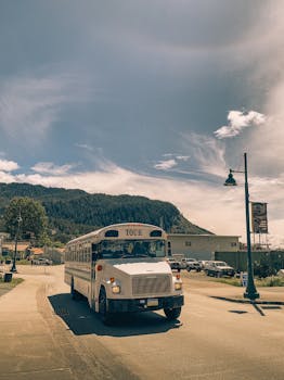 A tour bus drives through a picturesque street with mountains in the background in Haines, Alaska.