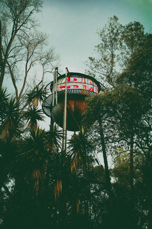 Free Vintage water tower surrounded by trees, blending history with nature in a captivating scene. Stock Photo
