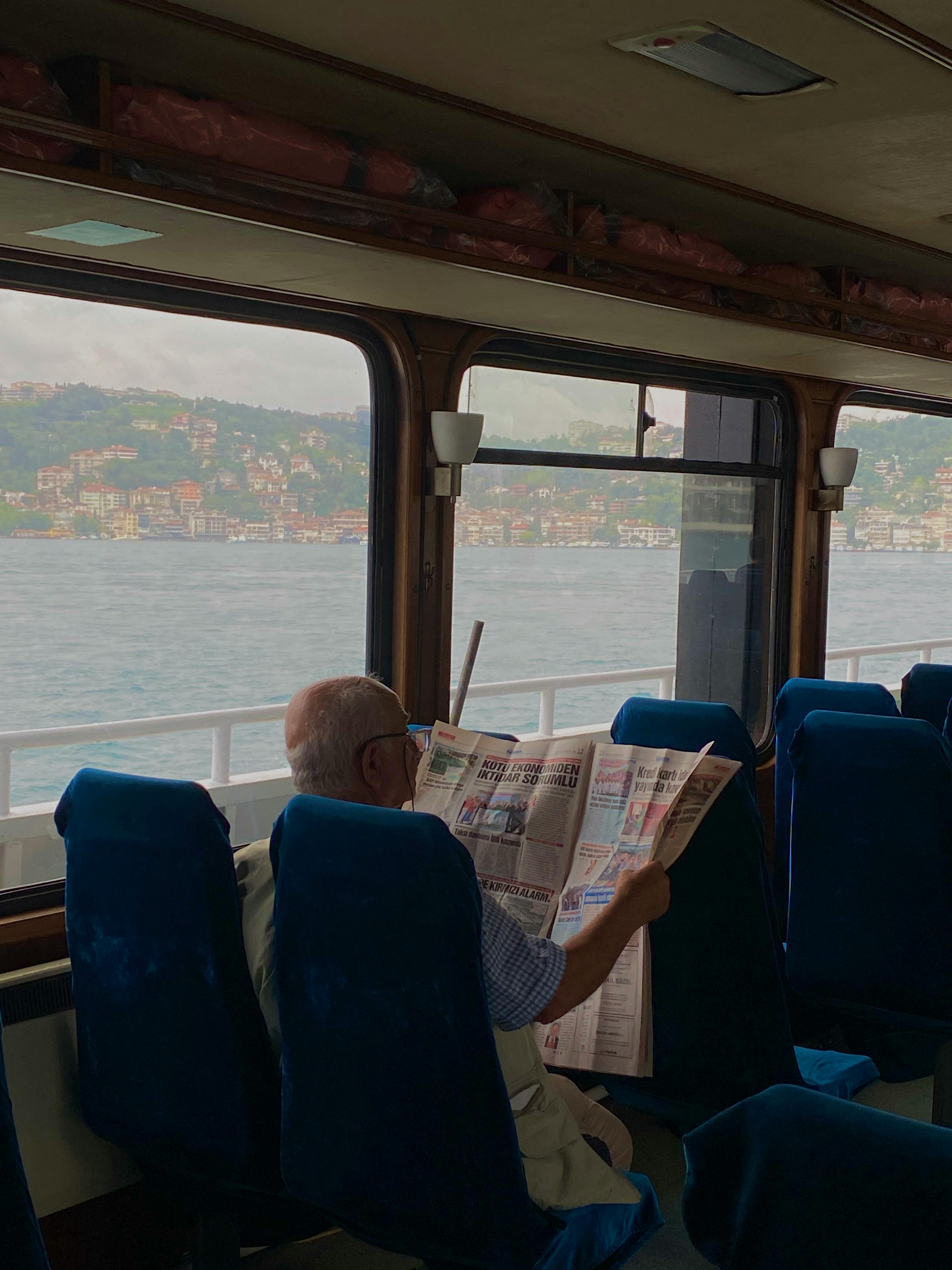 man reading a newspaper on a ferry