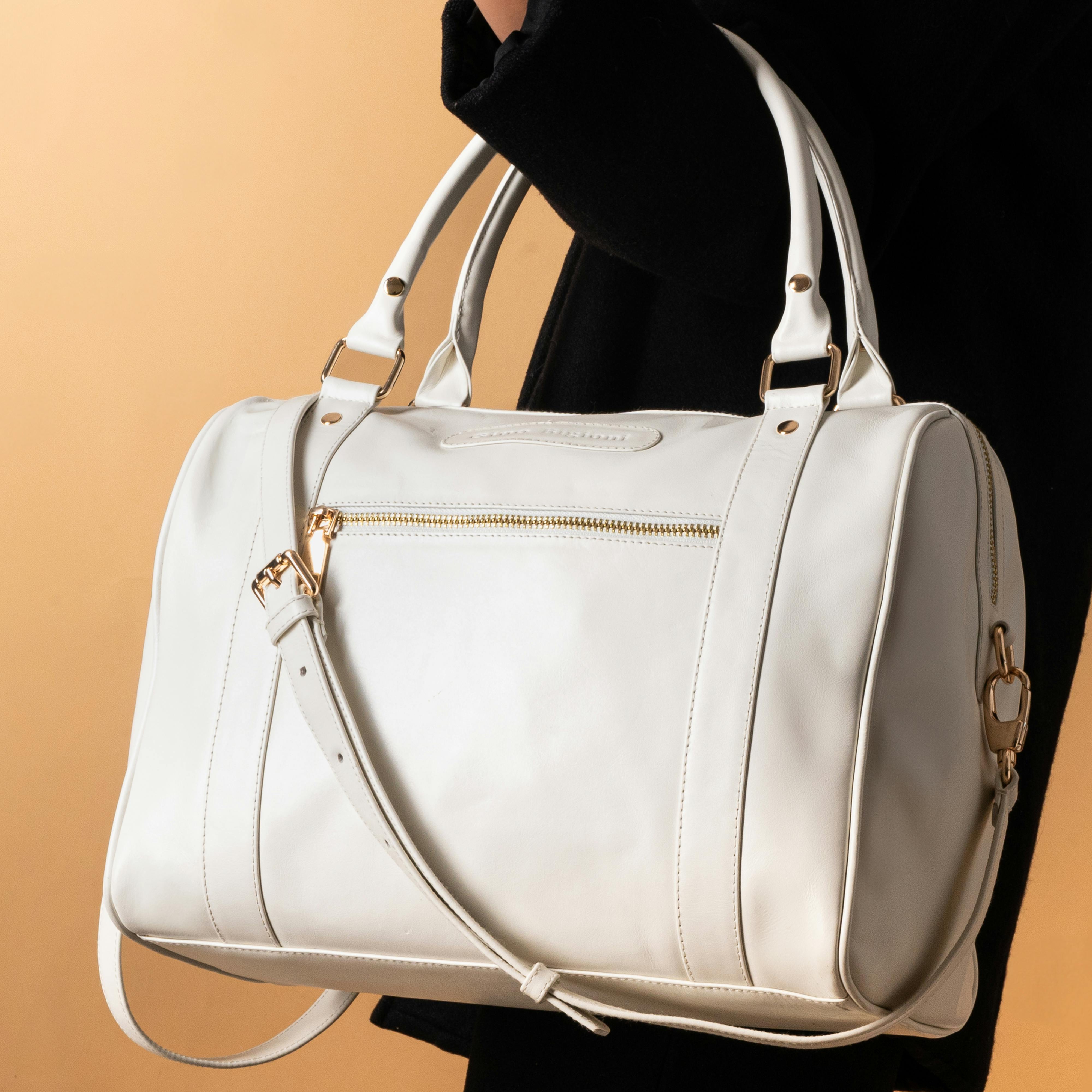 A woman holding a white leather duffel bag