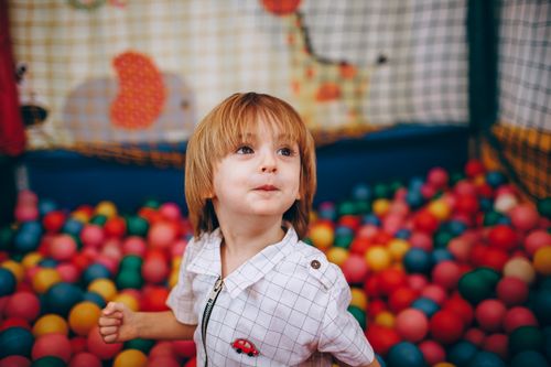Free A cheerful child having fun in a colorful indoor ball pit, capturing joy and playfulness. Stock Photo