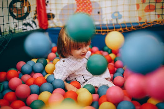 A cheerful child having fun in a colorful ball pit indoors.