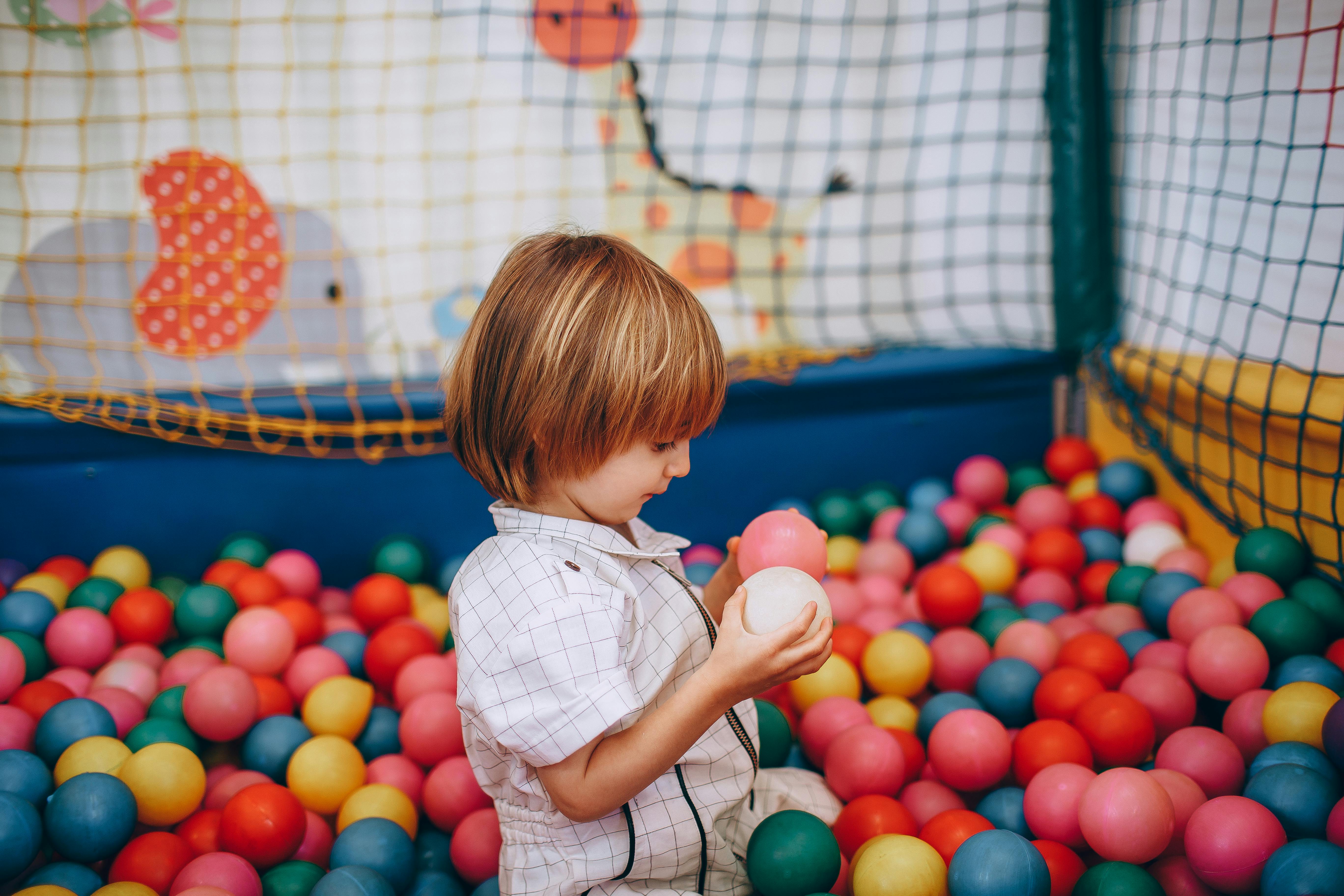 child boy playing with plastic colorful play balls in pool