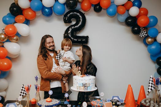 Joyful family celebrating a child's second birthday with balloons and cake.