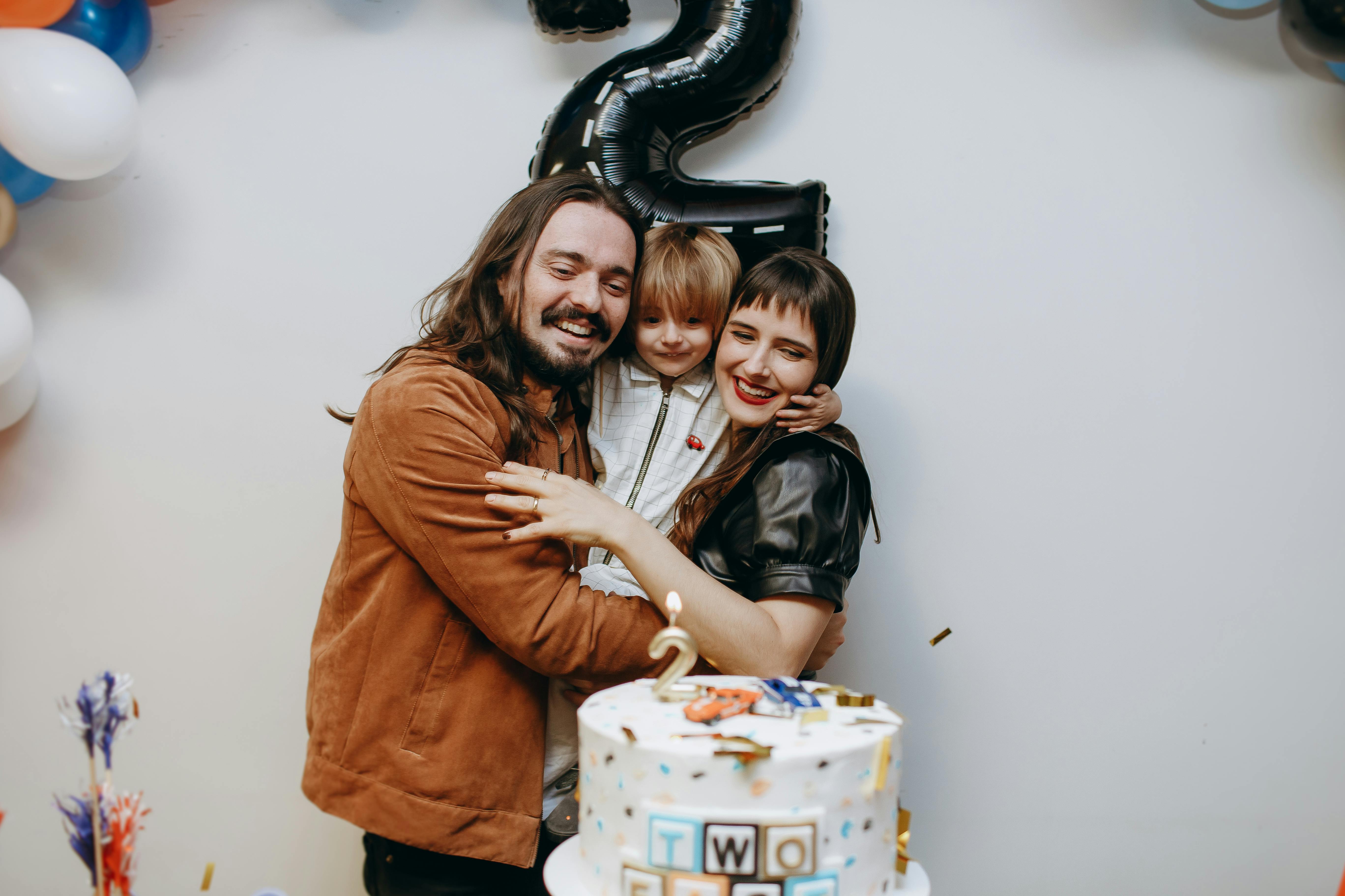 parents smiling holding their child on his birthday party