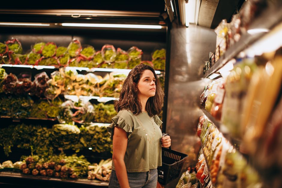 Cliente parcourant les rayons d'un supermarché avec un panier