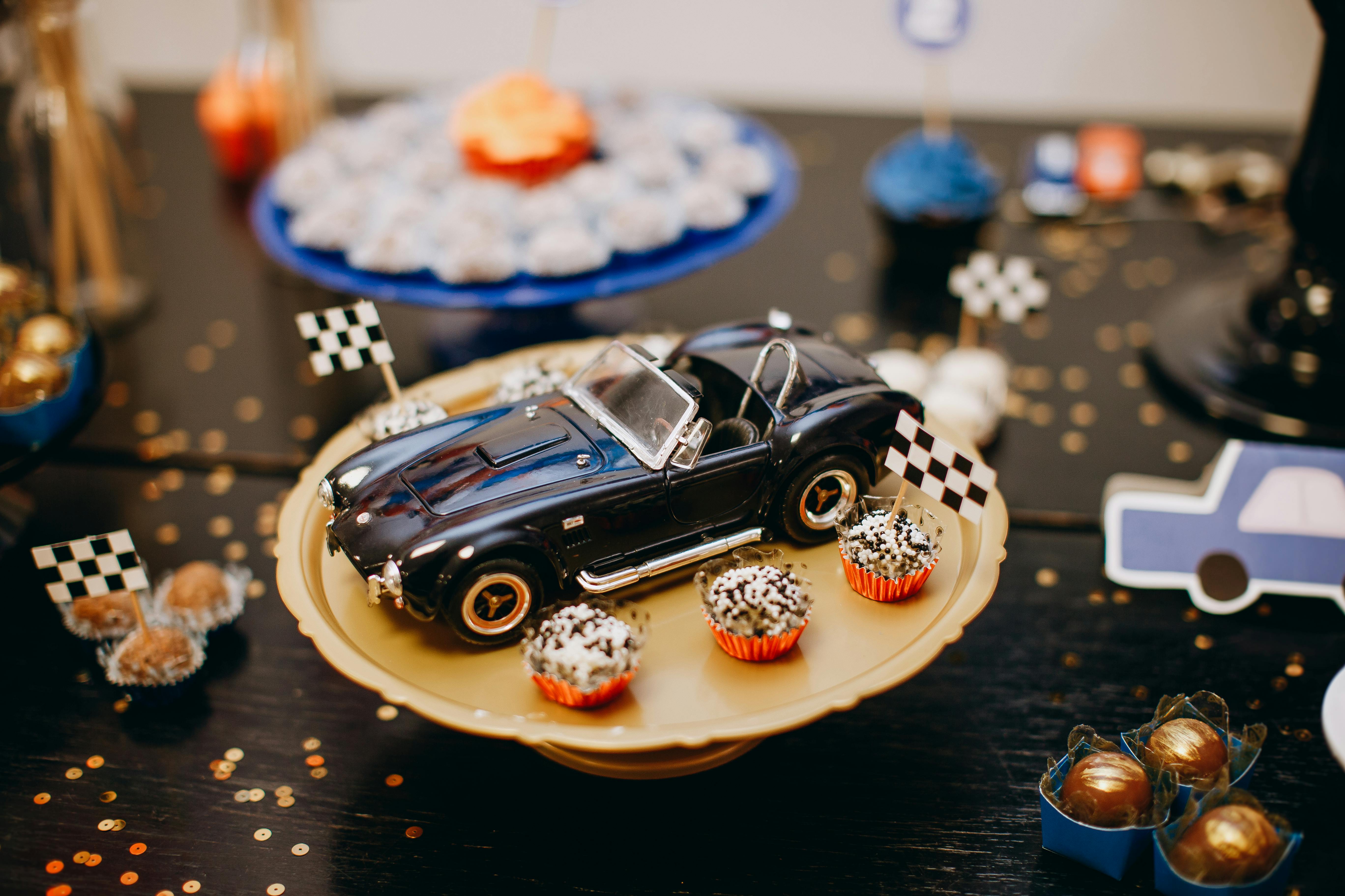 Miniature race car model with themed cupcakes on a party table, perfect for celebrations.