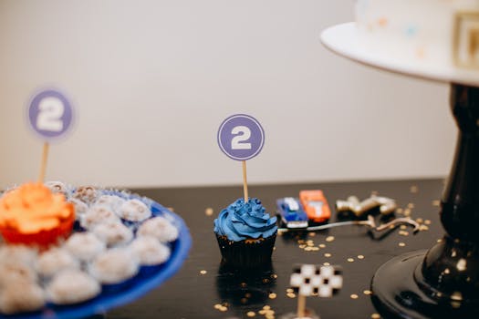 Colorful cupcakes and party decorations for a second birthday celebration indoors.