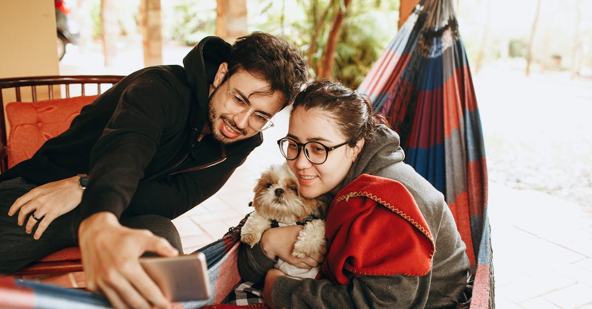 A man and woman sitting in a hammock with a dog