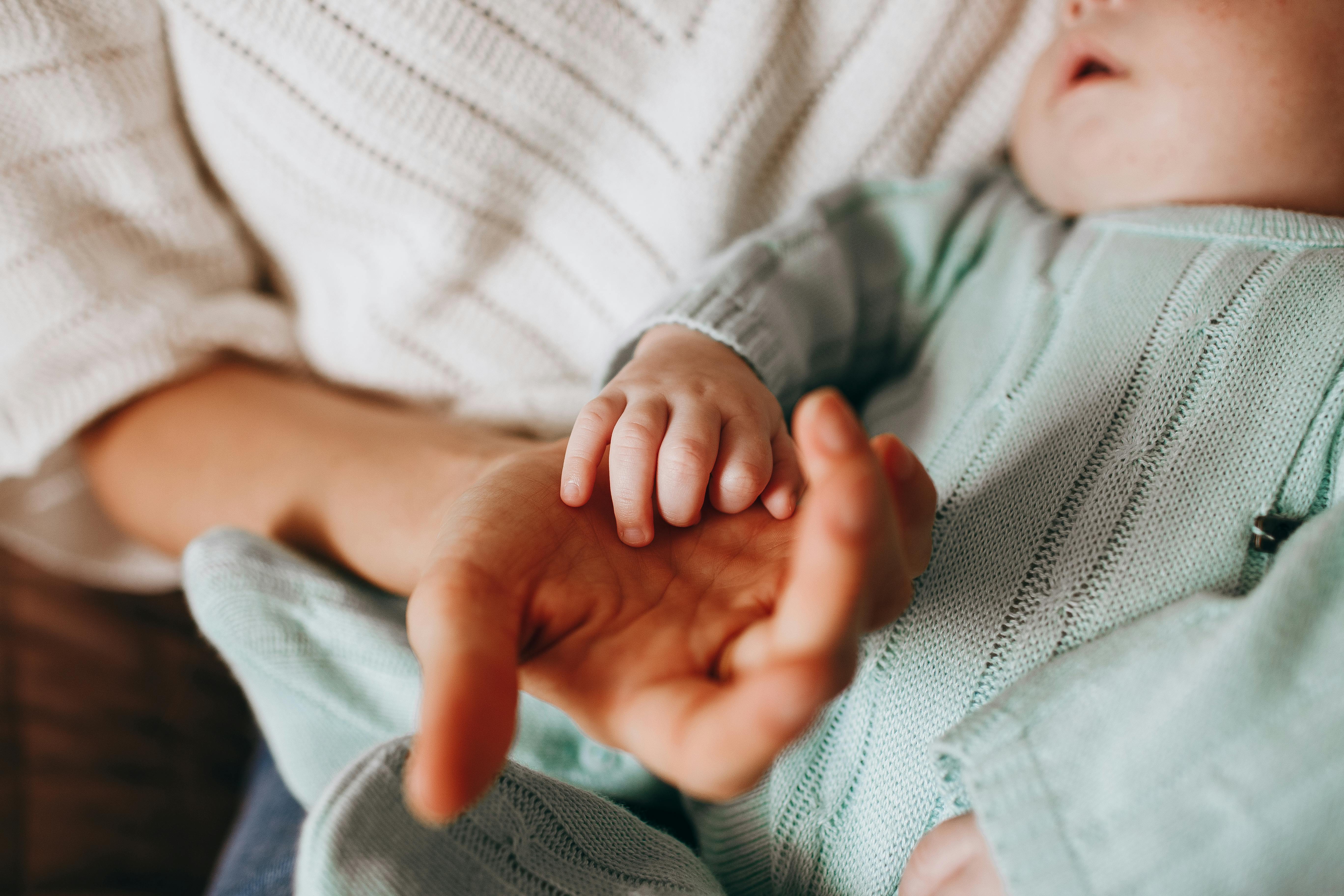 woman holding the hand of her baby son