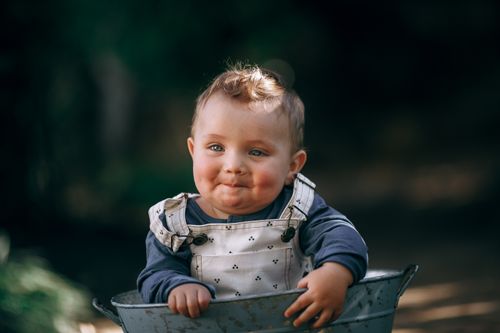Free Charming portrait of a baby in overalls sitting outdoors in natural light. Stock Photo