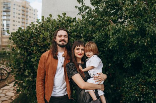 Free A joyful family portrait outdoors with lush greenery as background, exuding happiness and togetherness. Stock Photo