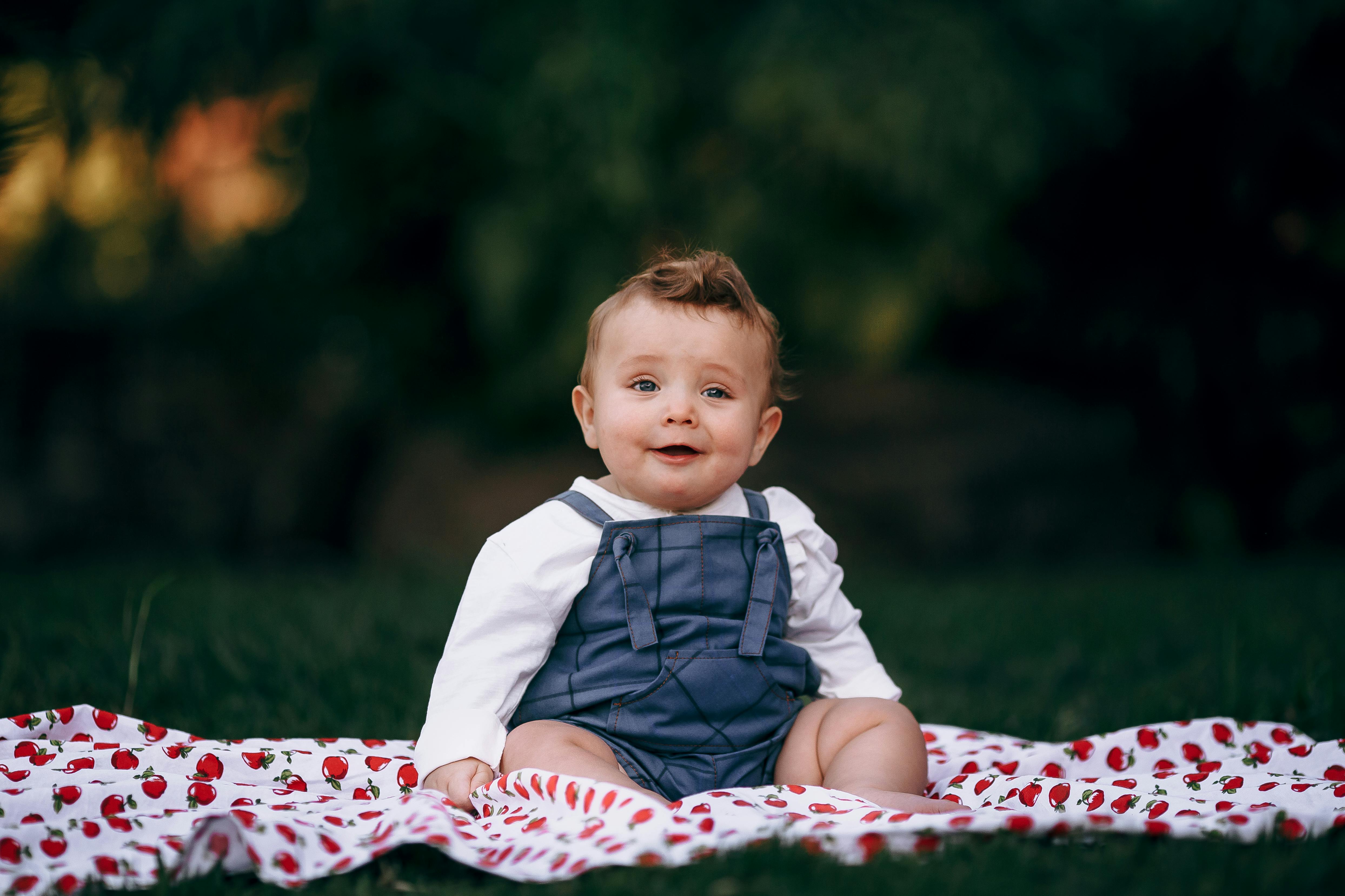 baby in overalls sitting on blanket