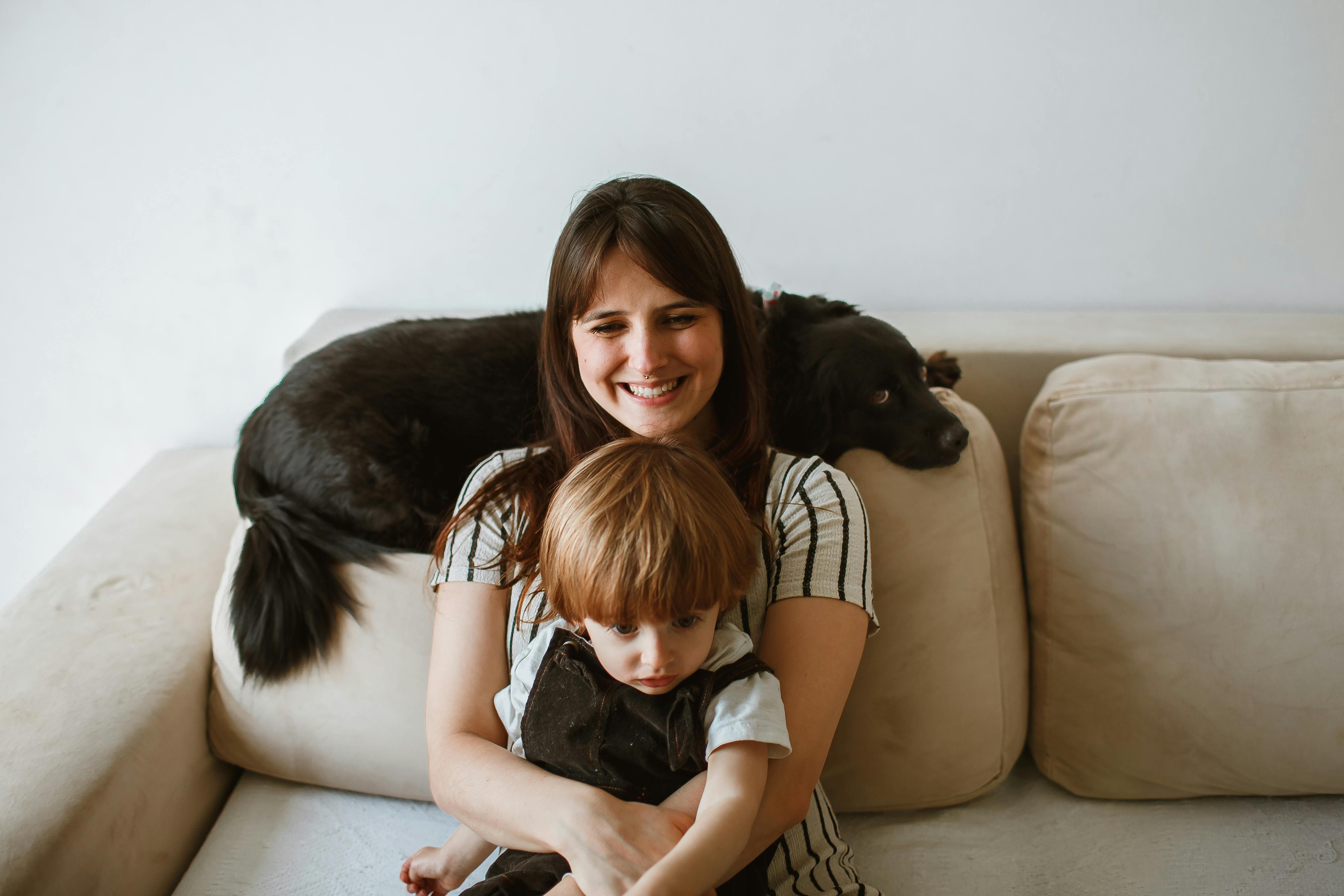 smiling mother sitting with son and dog on couch