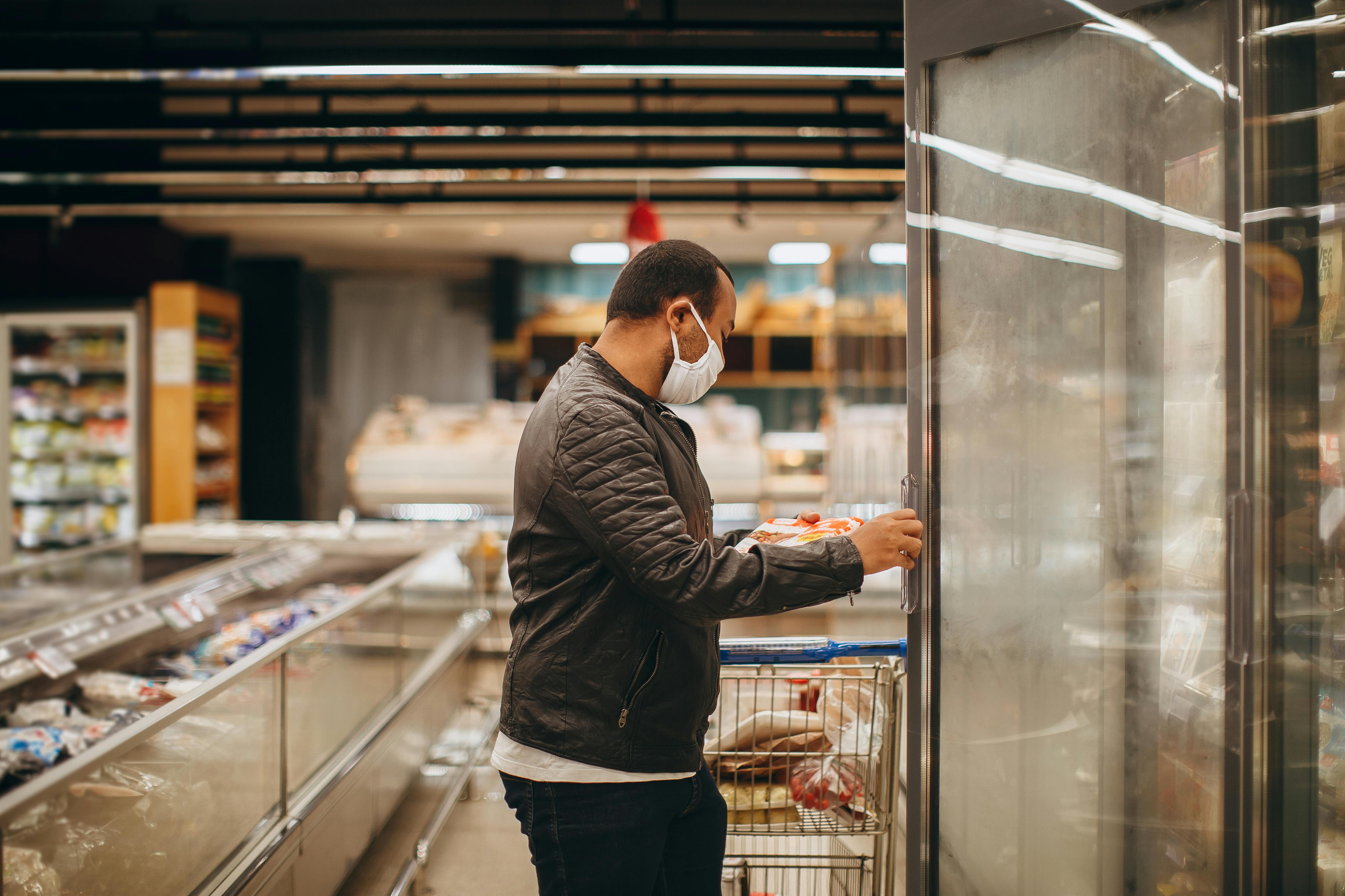 A person browsing the freezer aisle at a wholesale warehouse - restaurant depot upright freezer