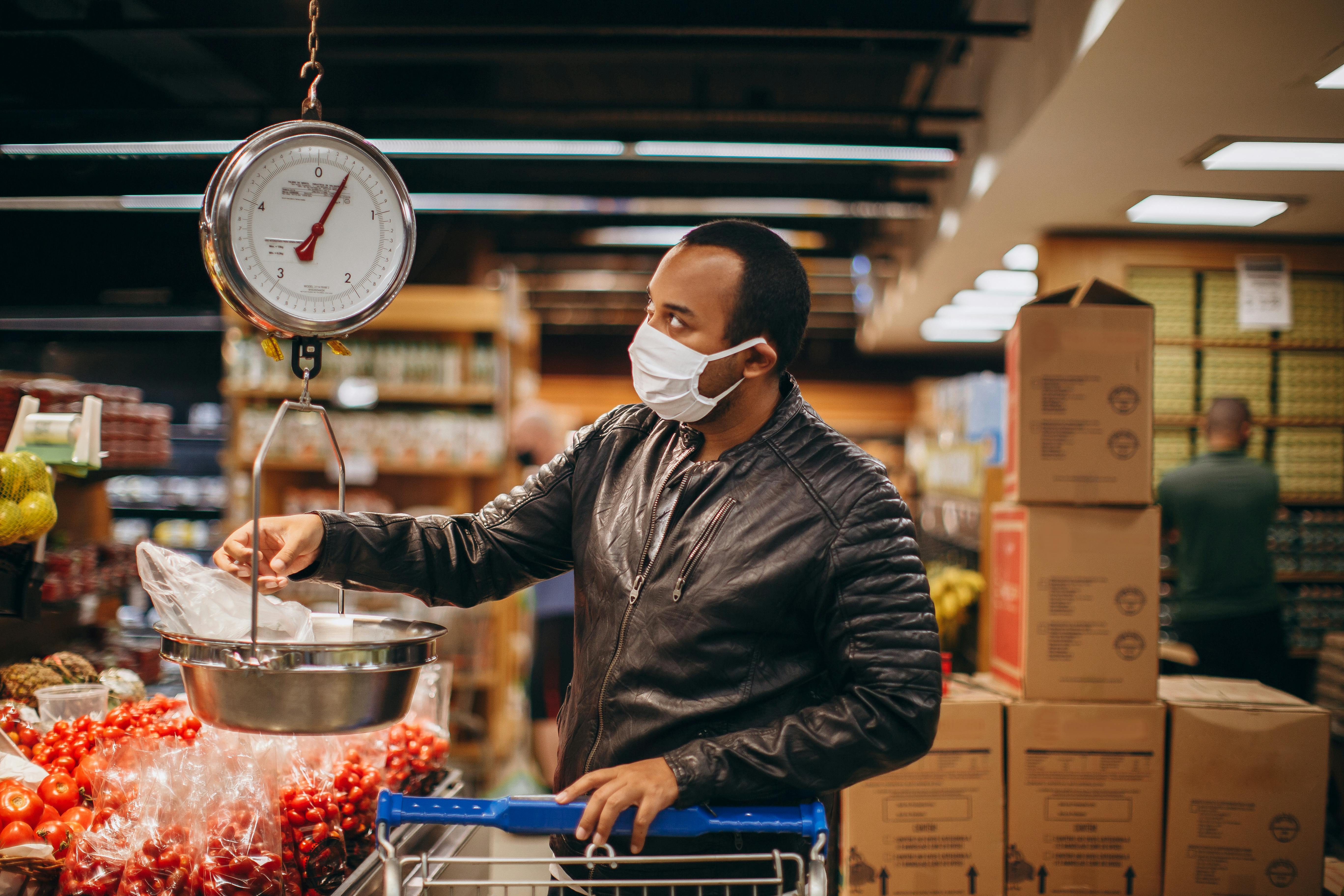 man in mask and black jacket shopping at supermarket