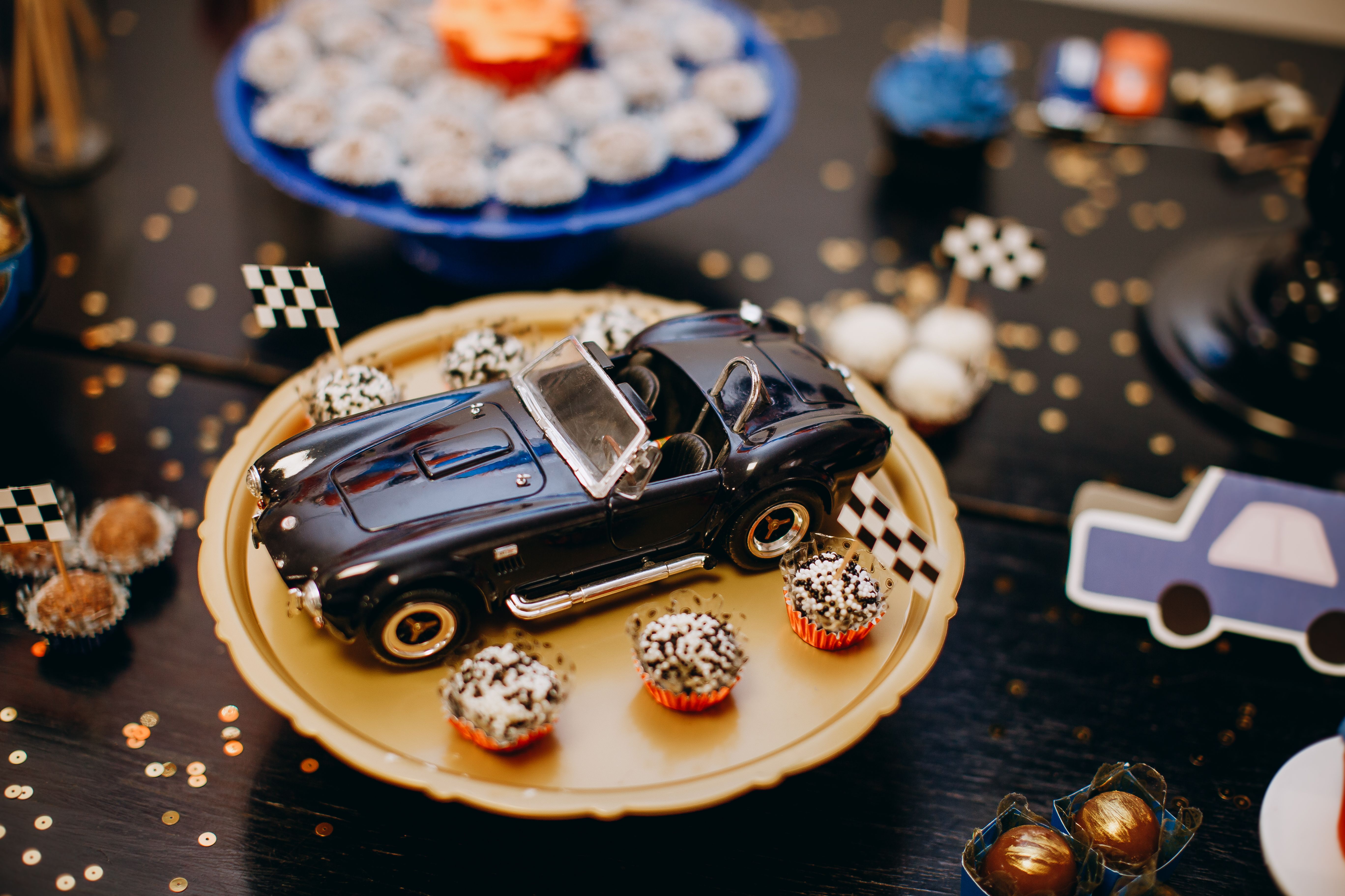 A stylish toy car displayed with decorated cupcakes on a festive plate, perfect for birthday themes.