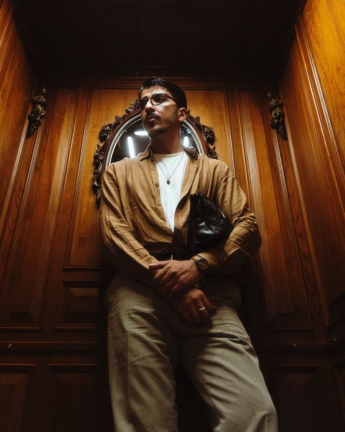 Free Fashionable man in a vintage wood-paneled room, showcasing modern style. Stock Photo