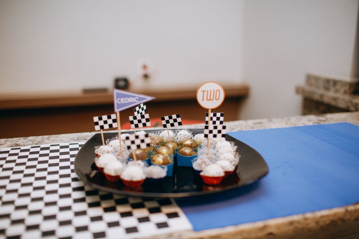 Race-themed dessert table with cupcakes and checkered flags for a birthday celebration. Stock Photo.