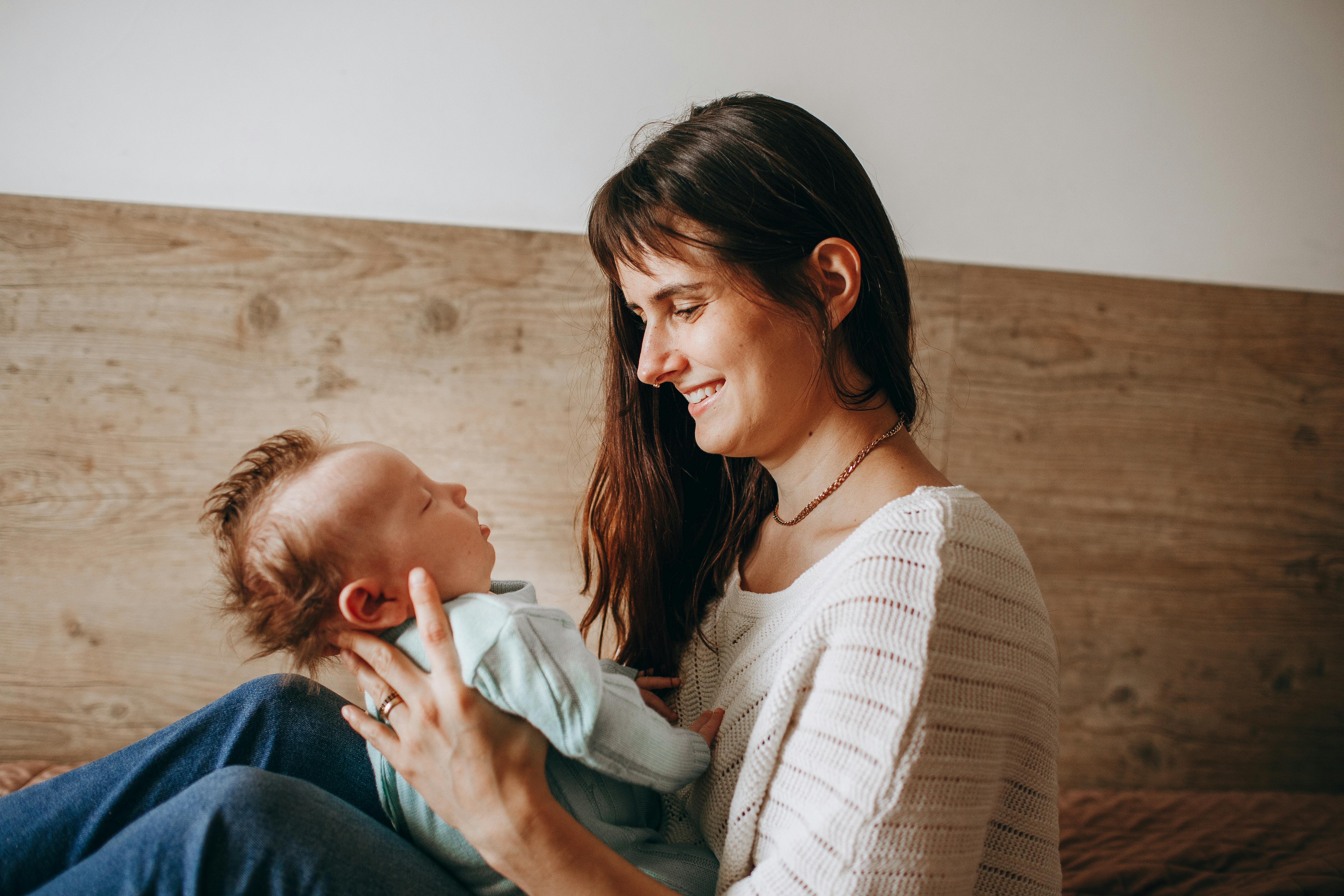 A tender moment between a mother and her baby with warm smiles indoors.