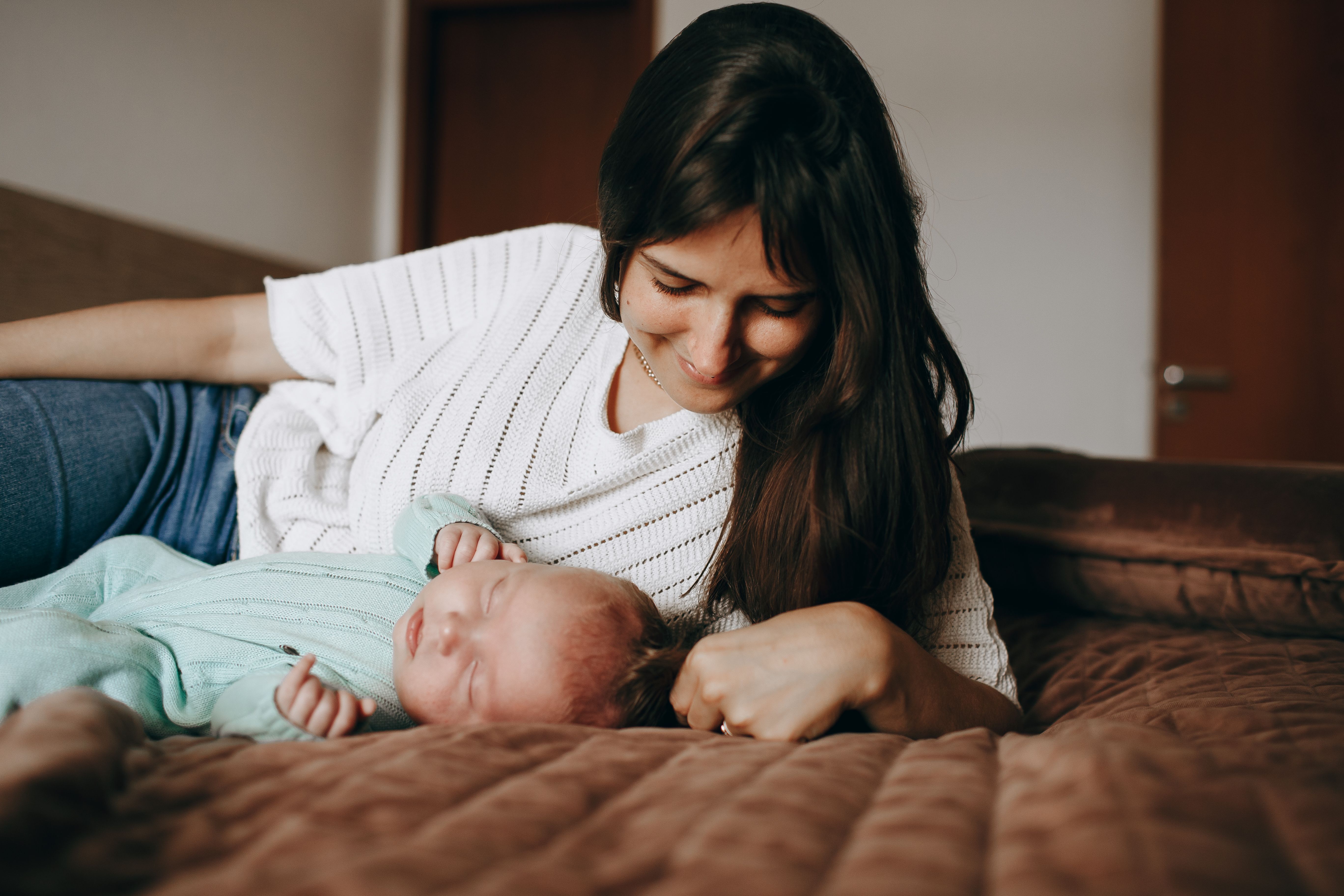 A mother and her baby enjoying a peaceful moment on a bed in a warm, cozy bedroom.