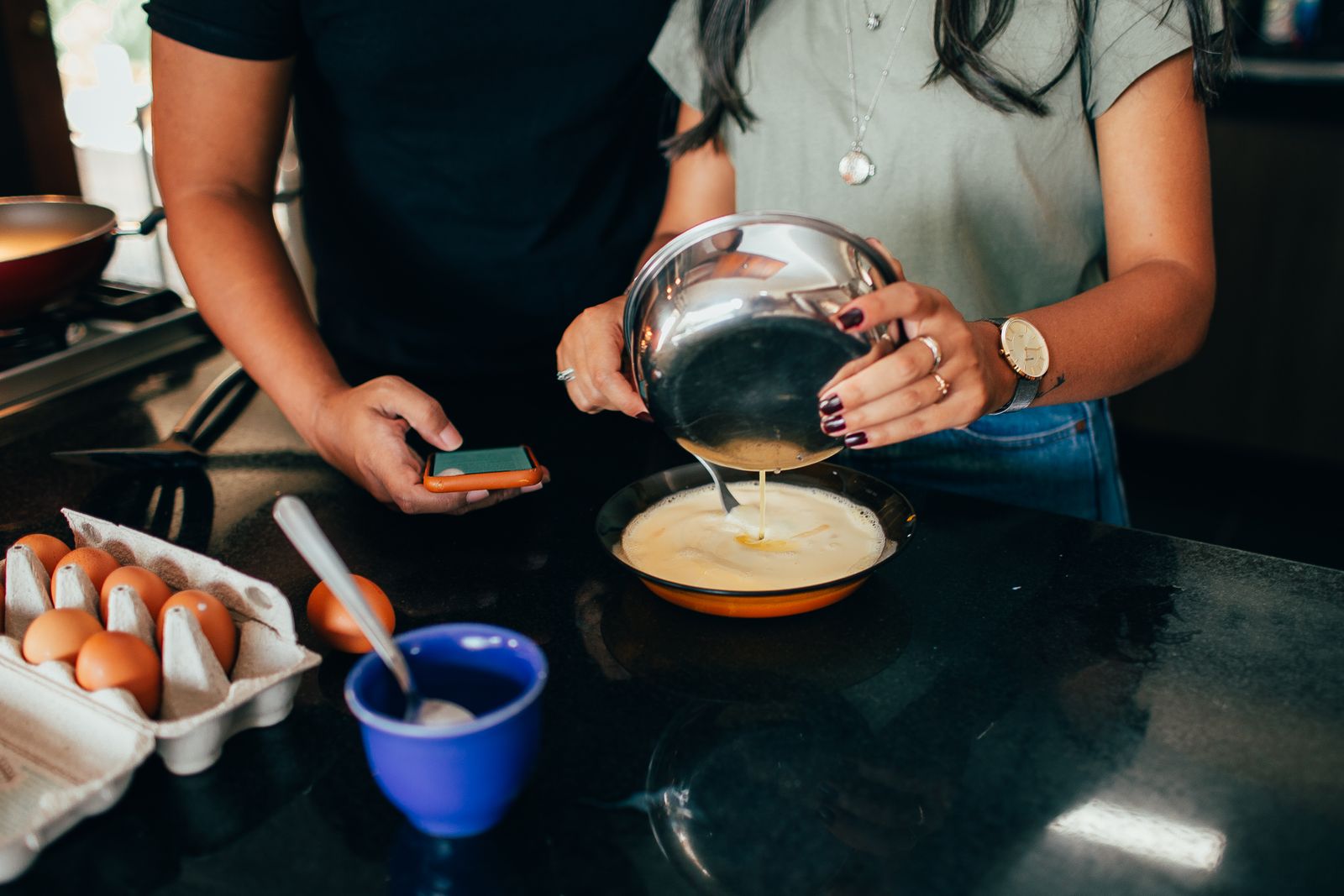 A couple cooking breakfast together, illustrating teamwork in a modern kitchen.