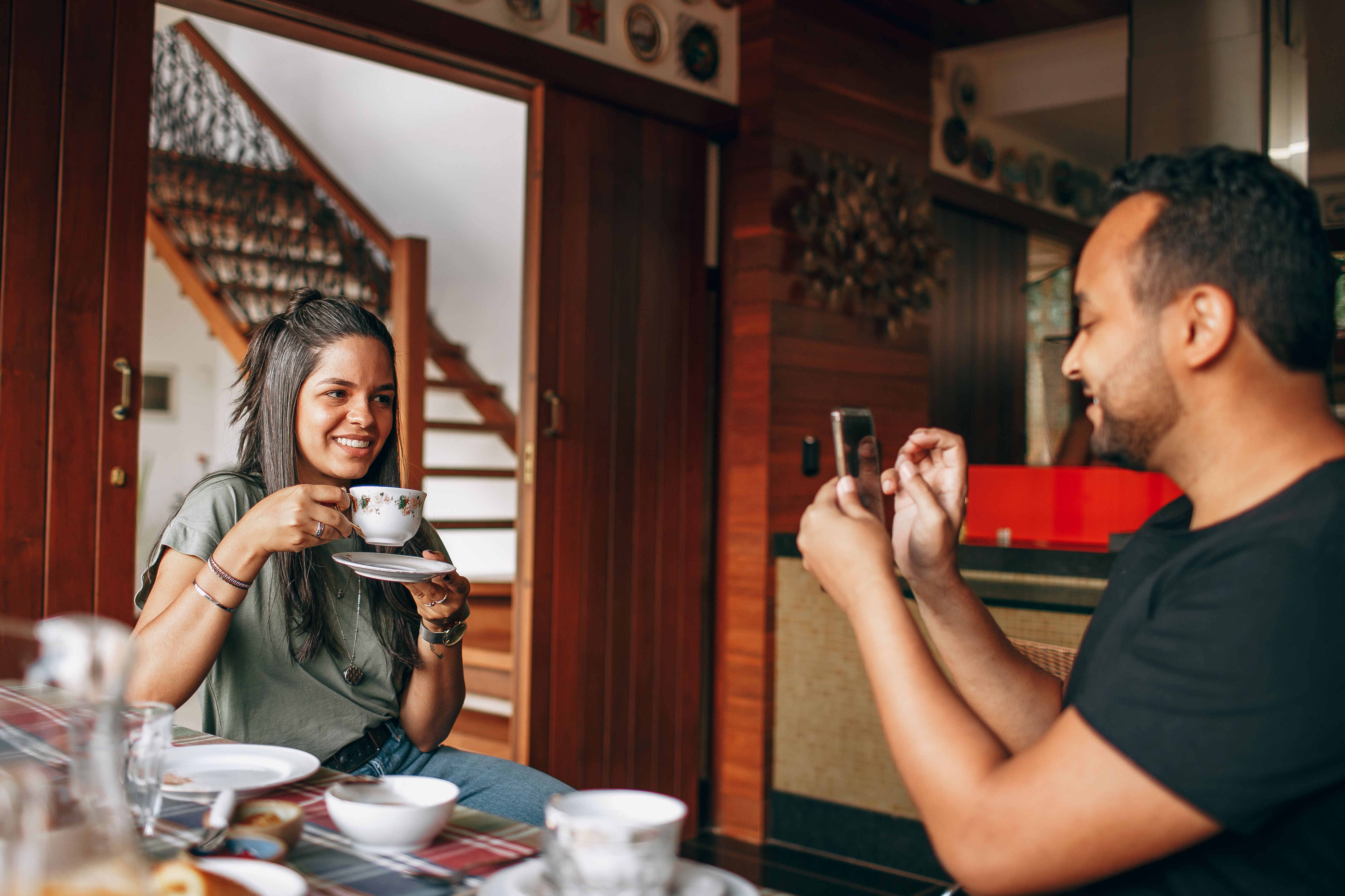 Casual scene of friends enjoying coffee indoors, capturing memories with a phone.